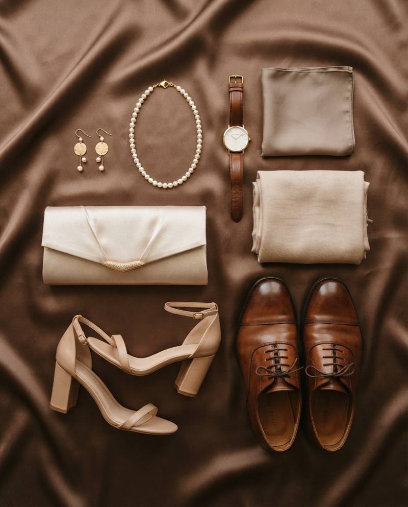 Gold earrings, pearls, a satin clutch, block heels and leather shoes on mocha satin